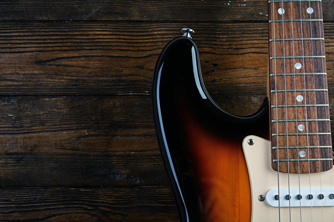 close-up-on-electric-guitar-on-vintage-old-wooden-background-e1648805464593.jpg